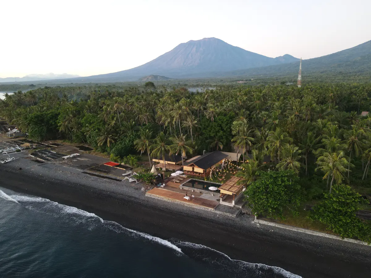 VELA Tianyar from the air, on the dark shore, with the mountain behind.