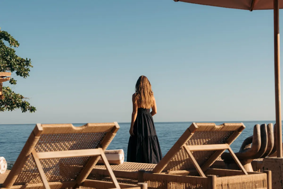 A woman looking out to sea from the deck, seen from behind.