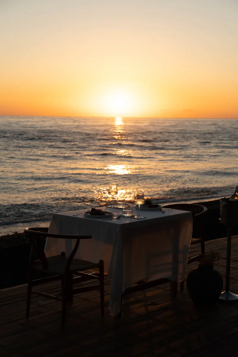 Sunrise over the sea, with a table laid by the water.
