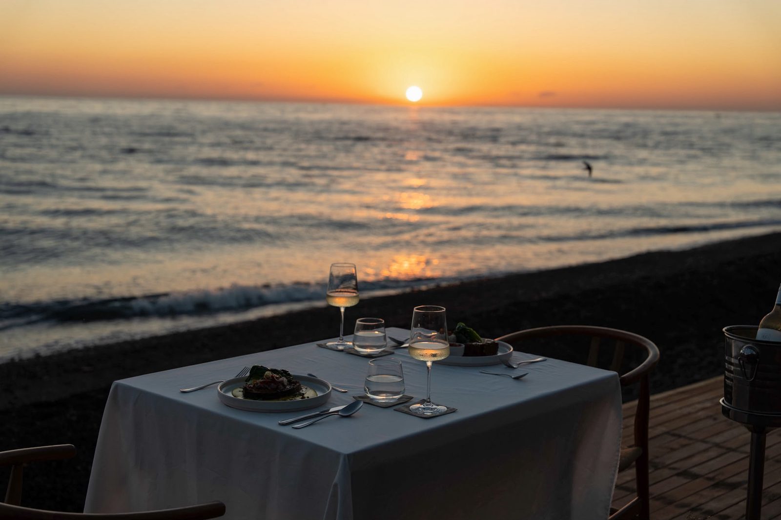 A table set on the deck at Saga as the sun goes down over the North Bali sea