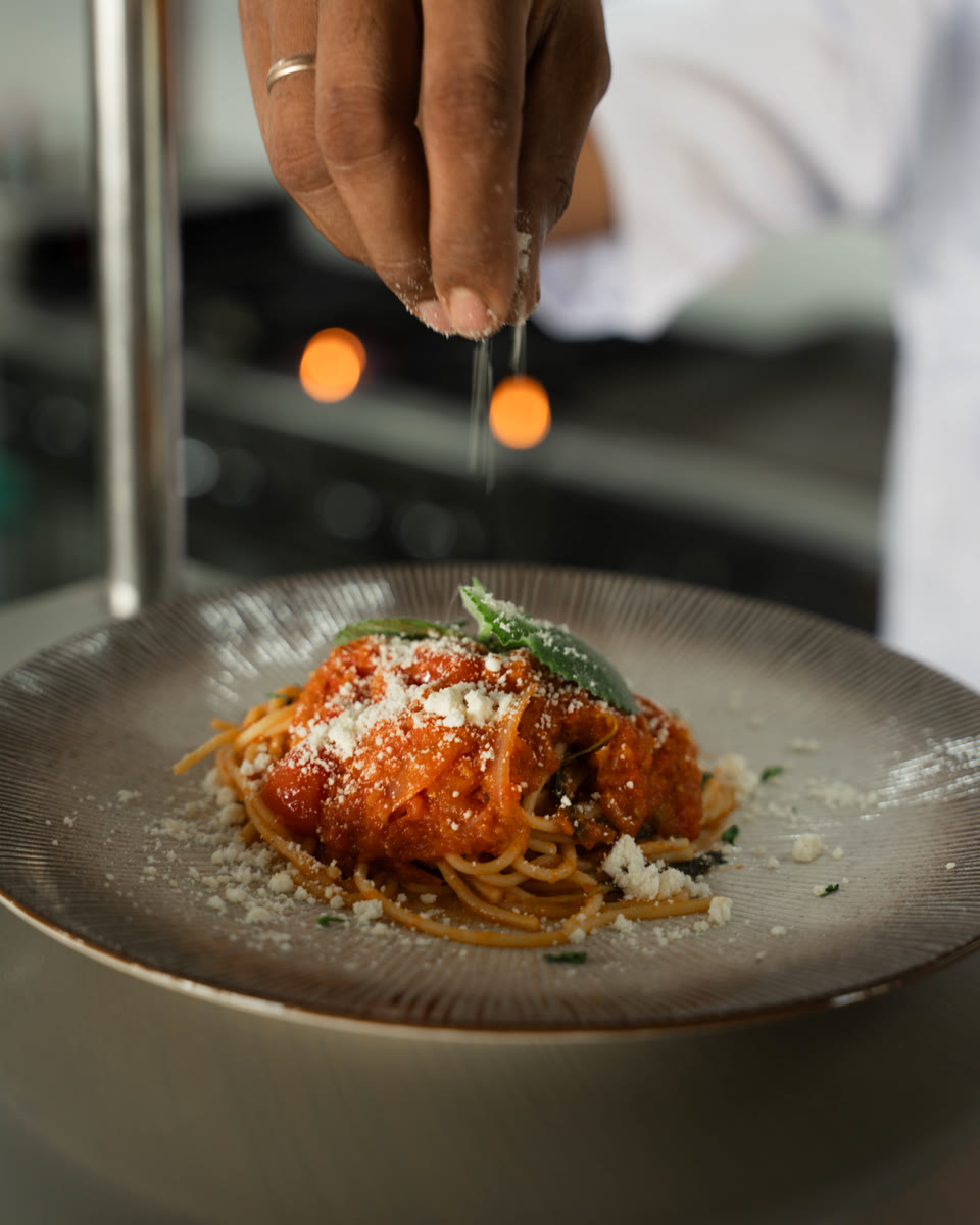 A chef finishing a plate of pasta at the Saga kitchen