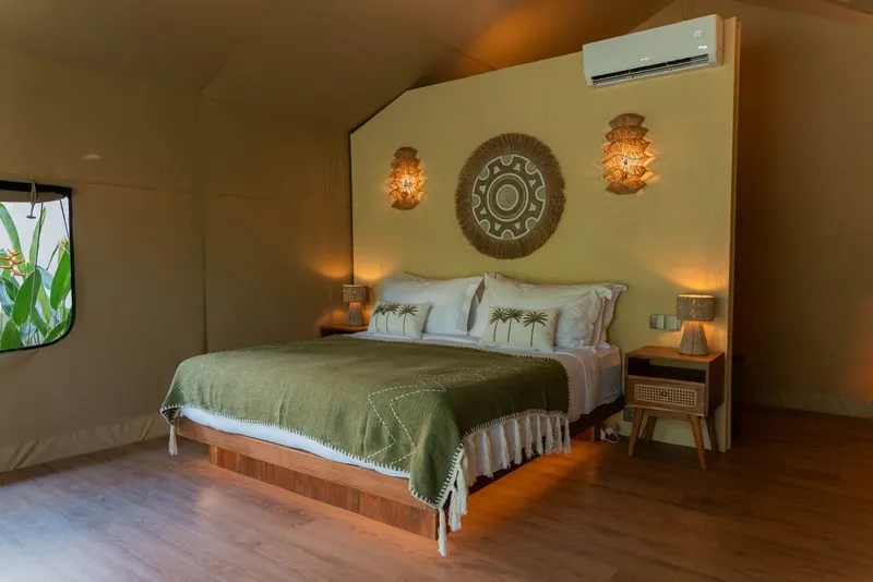 Segara's bed, dressed with palm-print cushions beneath woven sconces