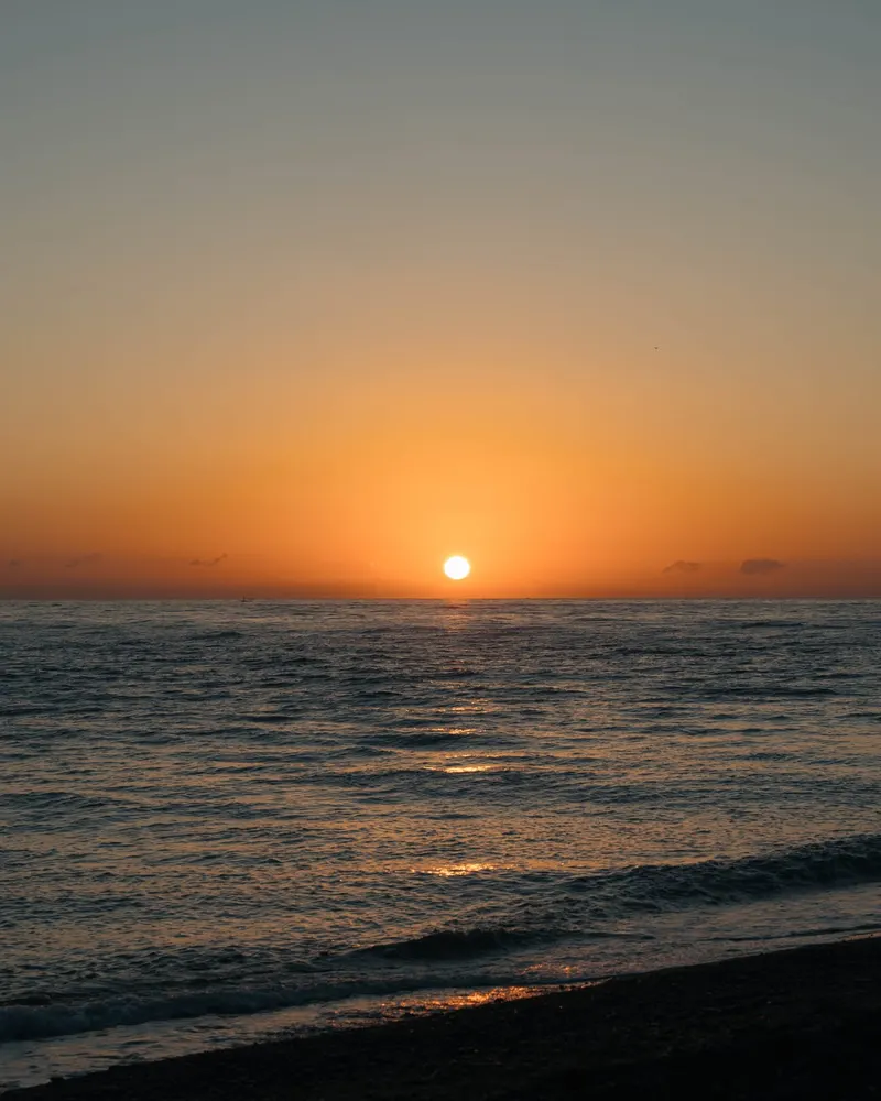 The sun just above the horizon over a calm sea off the north coast of Bali