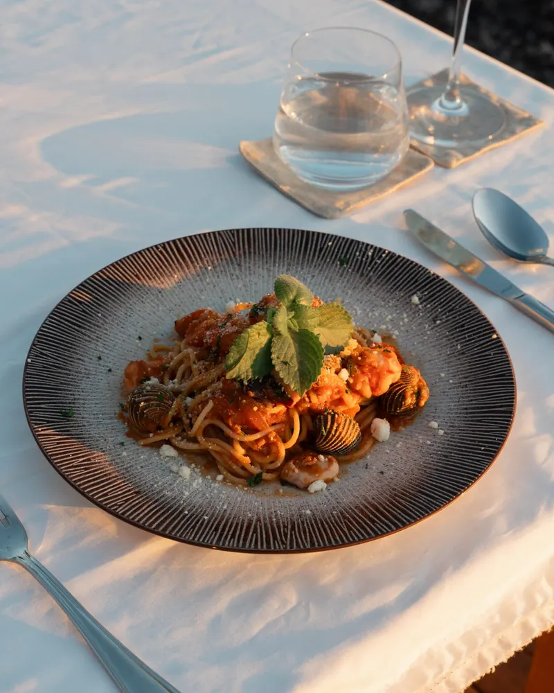 A plate from the Saga kitchen on a white cloth, a glass of water beside it, in the last of the sun