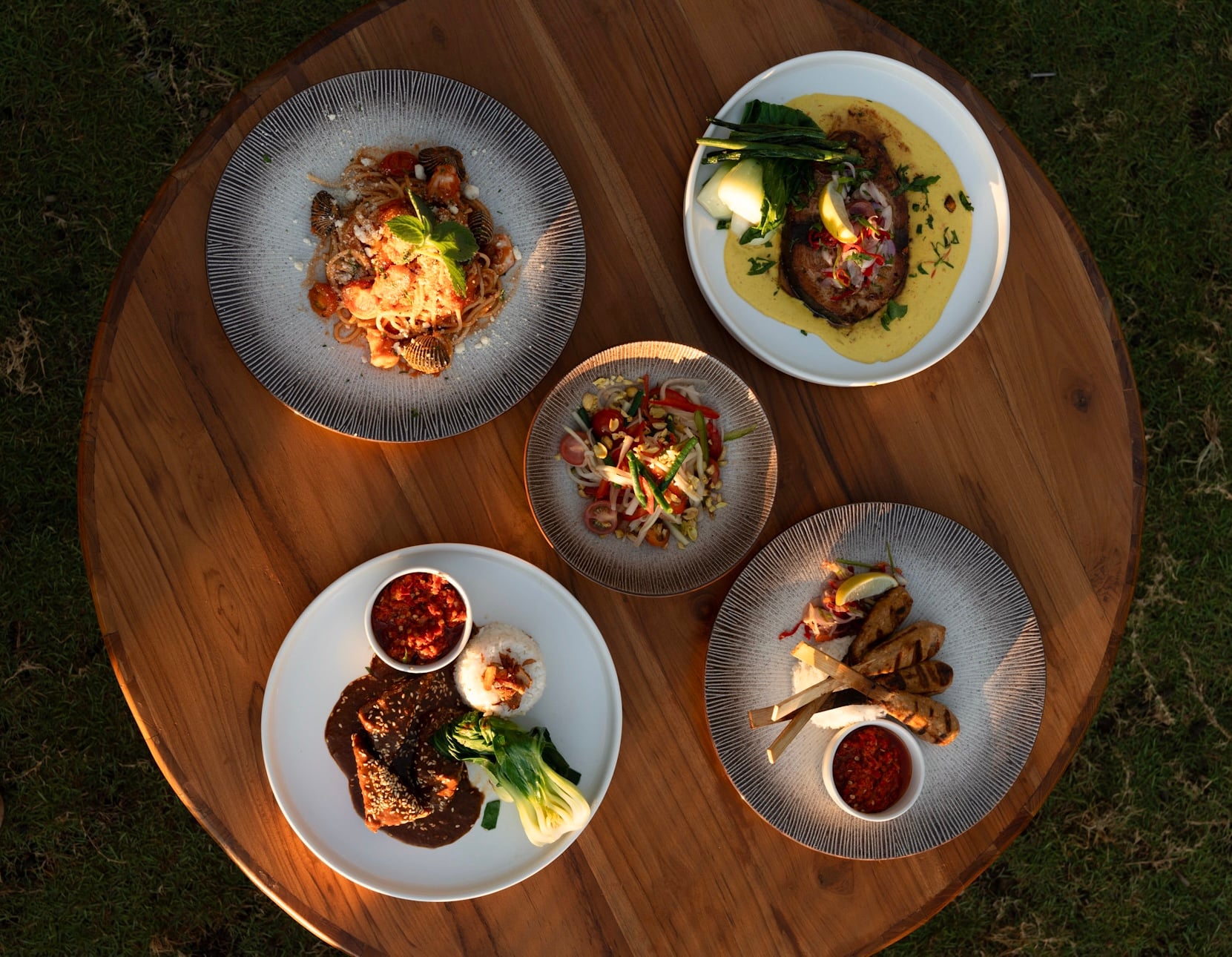 A table for two set on the deck at Saga as the sun drops over the North Bali sea
